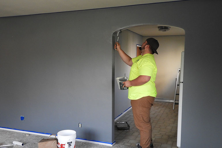 man painting grey wall